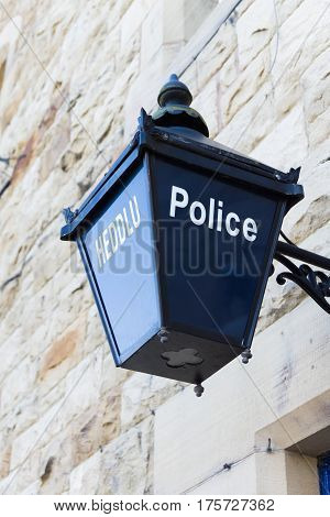 Old fashioned blue lamp outside a Welsh police station in both English and Welsh language