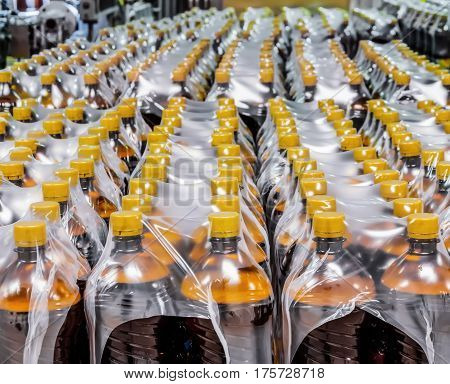 Packaging plastic bottles at the brewery. Packed shrink packaging film.