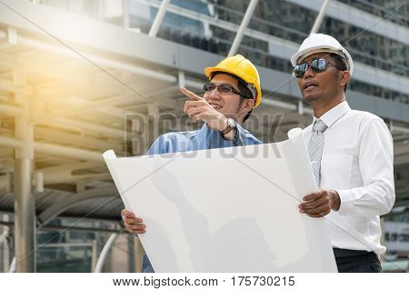 Engineer and Architect working at Construction Site with blueprint