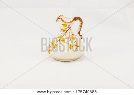 a white ceramic jug with tree branches and yellow leaves