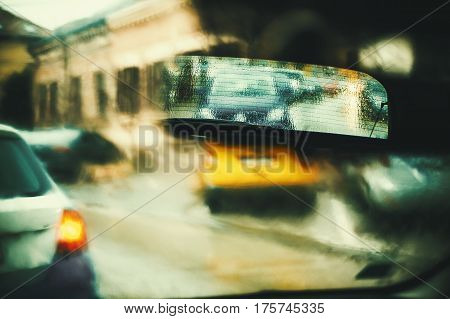 View from car during rain artistic blurry foreground with focus on rear view mirror.