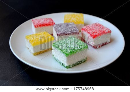 Multicolored marmalade sliced in pieces on a white plate - harm of sweet