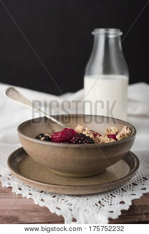 Milky soup with granola in brown bowl.