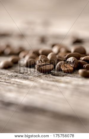 Selective focus macro view of coffee beans on old wooden table with copy space.