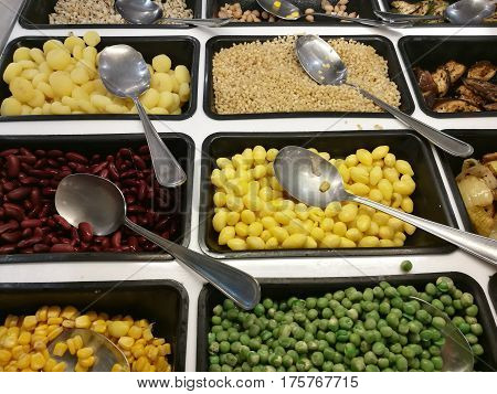 Salad bar with various fresh vegetables selection and spooncorn green peaslotus seedsred yellow beanwaternuteggplantaubergineonion focus-on-foreground with blur background