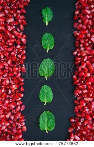 Pomegranate with mint on a black background