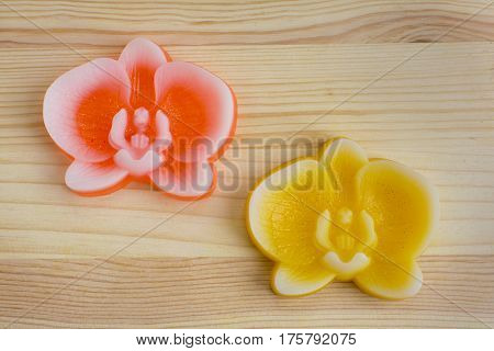 Original handmade soaps shaped like orchids on the natural wooden background.