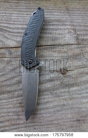 Knife with a plastic handle on a wooden background.