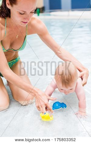 Baby playing in the water at indoor wsimming pool.
