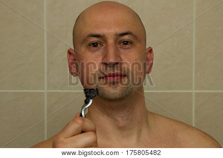 young guy with a razor in hand. Bald