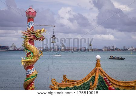 Golden dragon statue at Hean Boo Thean Kuanyin Chinese Buddhist temple in Penang, Malaysia with port in background