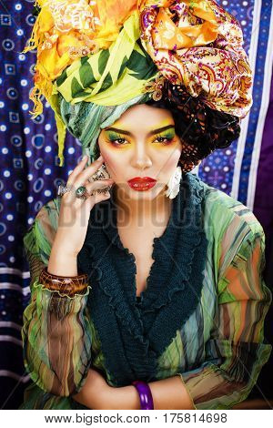 beauty bright woman with creative bright make up, many shawls on head like cubian, ethno look closeup