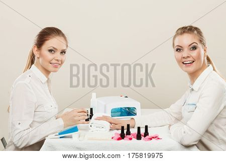Relaxing time and wellness day concept. Blonde elegant woman visiting professional manicurist salon. Beautician makes perfect nails to client.