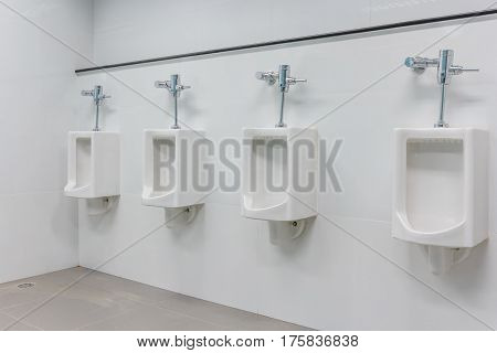 White urinals in clean men public toilet room interior.