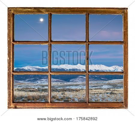 full moon over snowy Medicine Bow Mountains, North Park near Walden, Colorado as seen through vintage sash window
