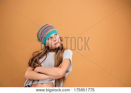 The face of sad teen girl in hat on brown studio background