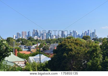 city skyline against blue sky with housing and trees in foreground