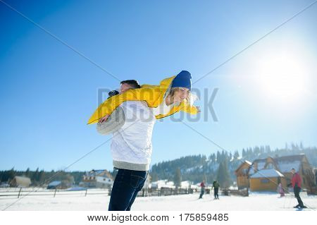 Young man holding in his arms his girlfriend. Man sturdily built easily picks up a fragile girl. Young people having fun. Against the background of the blue sky.