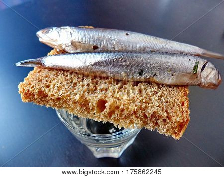 A bread, spicy salting anchovy  and a glass of vodka. Closeup. Gorgeous home appetizer under a glass of vodka. Natural food. Traditional Dishes of Russian Cuisine.