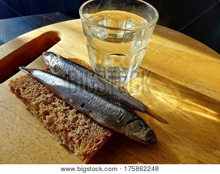 A bread, spicy salting anchovy  and a glass of vodka. Closeup. Gorgeous home appetizer under a glass of vodka. Natural food. Traditional Dishes of Russian Cuisine.