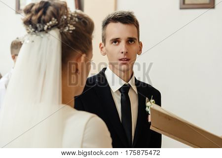 Happy Stylish Bride And Elegant Groom Exchanging Vows At Catholic Wedding Ceremony At Church