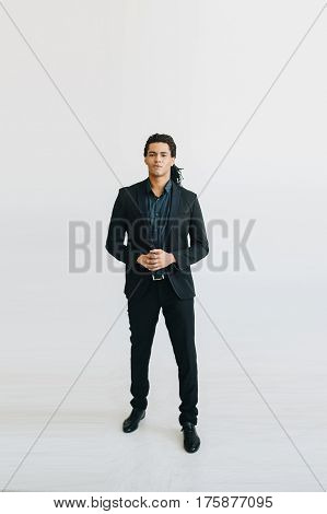 Happy young businessman in black suite and blue shirt standing over white background. Portrait of a handsome  boy. Color