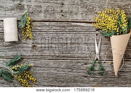 Make bouquet of mimosa. bandages twine and scissors on rustic wooden table. Copy space for text. top view