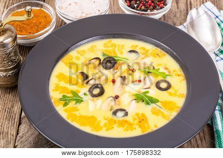 Vegetable soup puree with mussels in black plate on wooden background. Studio Photo