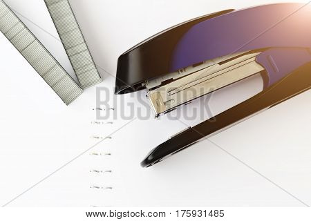 Stapler with staples on white paper. Staples in paper close-up. Office equipment concept.