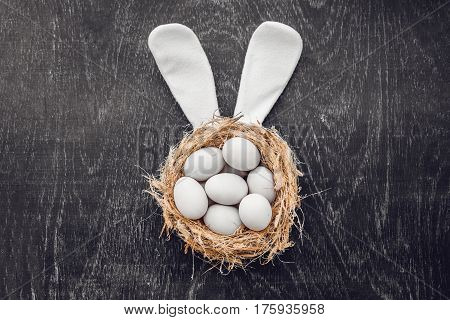 A Nest With Three White Easter Eggs And Bunny Ears At Home On Easter Day. Celebrating Easter At Spri