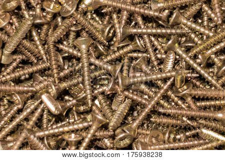 More self-tapping screws golden color. Background, tools.