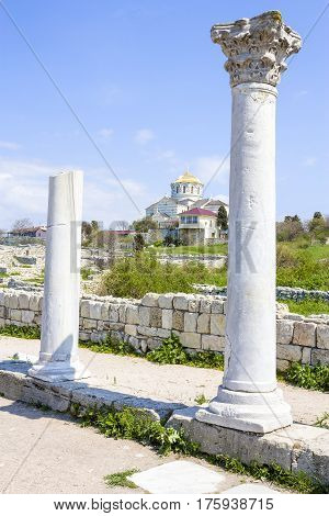 two ancient greek columns and orthodox church against the background