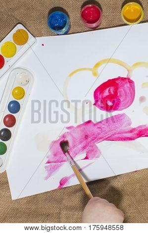Brush and colorful paints on a child's picture.