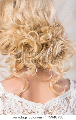 the blonde with a beautiful wedding hairstyle close up. the easy curls on a blonde hair collected in a free bunch. the bride in a lacy wedding dress.