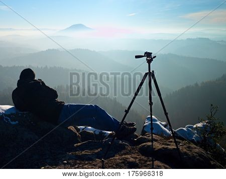 Man Takes Photos With Camera On Sharp Rock. Dreamy Fogy Landscape