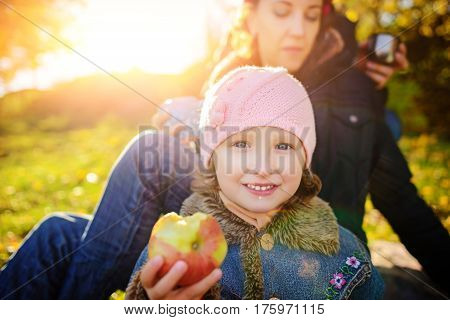 Girl sitting on the grass with an apple in his hand early autumn