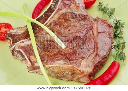 cibo di carne: arrosto nervatura sul piatto verde con timo pepe e pomodoro isolato su sfondo bianco