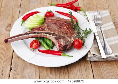 cibo di carne: arrosto nervatura sul piatto bianco con pepe timo e pomodoro sul tavolo di legno