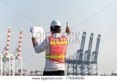 The man engineer working with container Cargo freight ship in shipyard at dusk for Logistic Import Export background