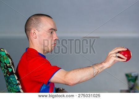 Boccia. A Disabled Sportsman Sitting In A Wheelchair Holding A Little Red Ball For Playing Boccia. S