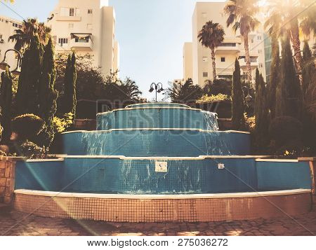 Residential Buildings And Fountain Surrounded With Green Plants In  Rishon Le Zion.