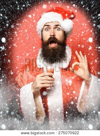 Handsome Bearded Santa Claus Man With Long Beard On Surprisedface Holding Glass Of Alcoholic Shot In