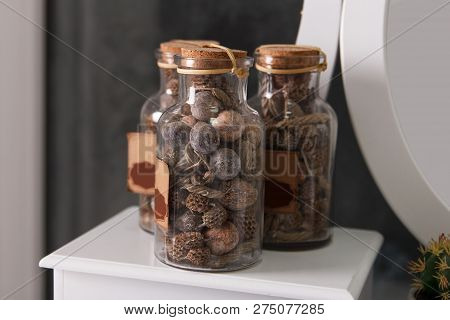 Three Decorative Glass Jars With Dry Nuts And Dry Stalks Decorate A Room Interior