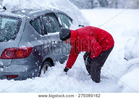 Young Man Is Cleaning Clean Off His Car Of Snow Cover By Brush. Snow Covered Car.