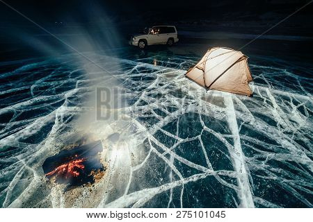 Fire On Ice At Night. Campground On Ice. Tent Stands Next To Bonfire. Lake Baikal. Nearby There Is C
