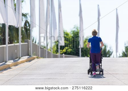 young healthy mother jogging while pushing a baby stroller at city park