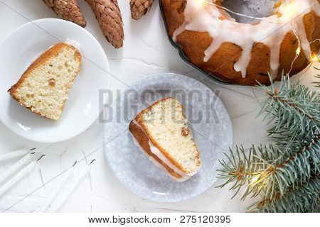 Pie With Raisins And Icing From Powdered Sugar On The Background Of Fir Branches And Garlands. Rusti
