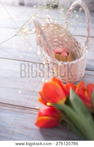 Tulips On A Wooden Background With Marshmallows In A Wooden Basket.