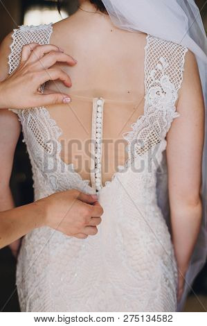 Bridesmaids Helping Bride Get Dressed In The Morning. Hands On Buttons On  Amazing Gown Of Gorgeous