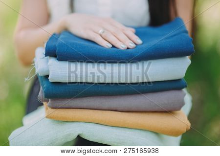 Cropped Image Of Smiling Seamstress Holding Stack Of Colored Fabric